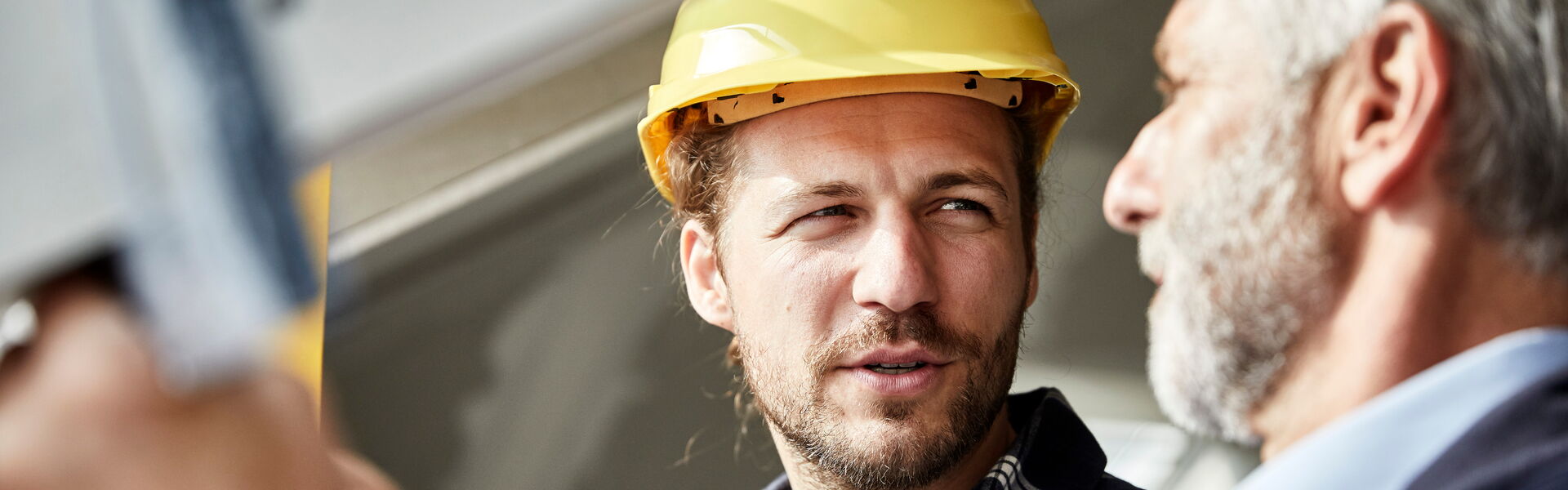 Ein junger Bauleiter mit einem älteren Kollegen auf der Baustelle